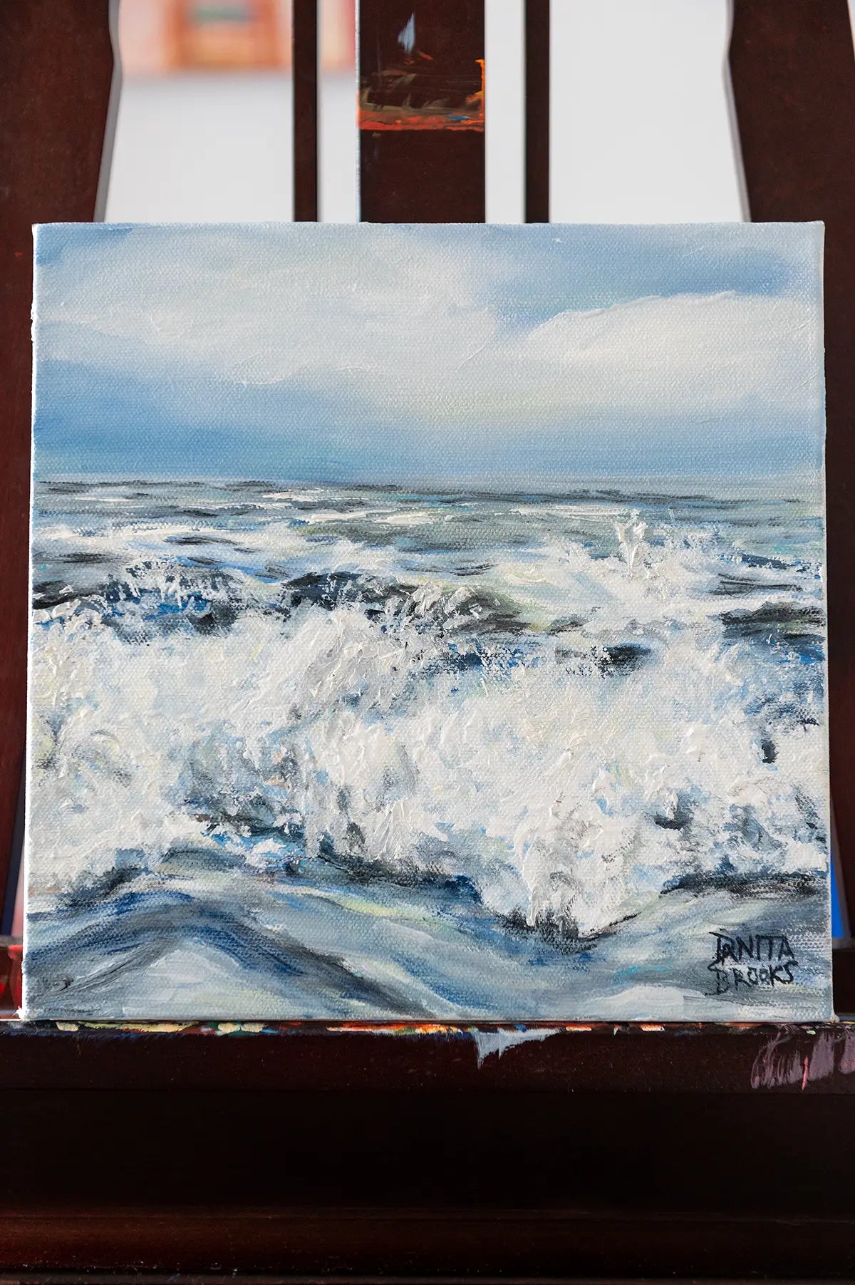 Original ocean wave oil painting titled "Alive" by Danita Brooks, displayed on an easel with natural light