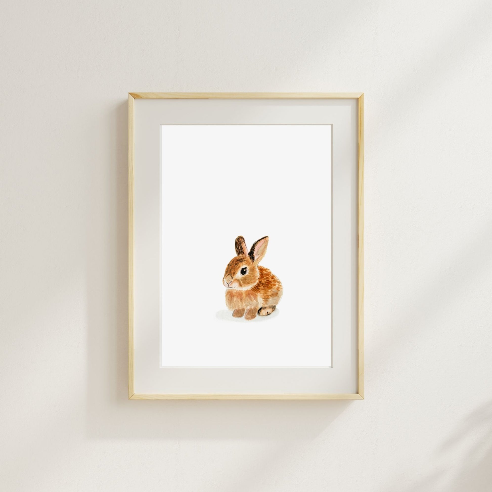 Woodland nursery watercolor bunny print – soft and playful animal wall art for kids room here shown in a wood frame with a cream mat