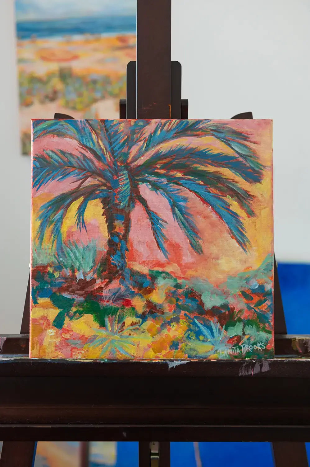 Original palm tree painting titled "Everlasting Sunset" by Danita Brooks, shown on the easel and displayed in natural light
