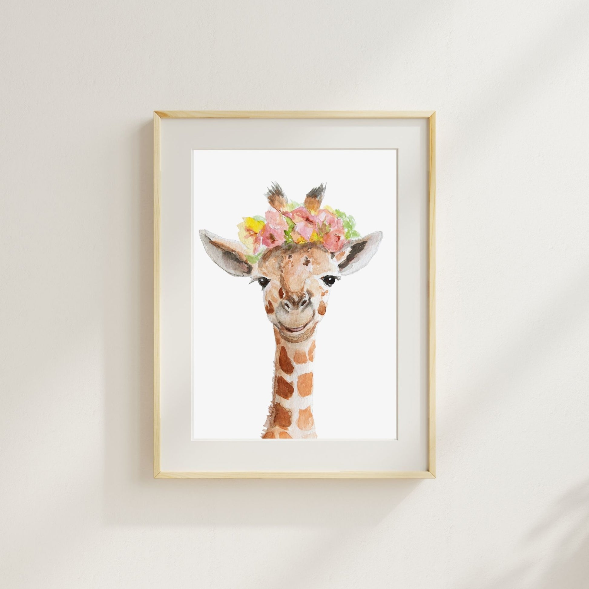 Giraffe with flower crown watercolor print matted and framed on wall in nursery setting