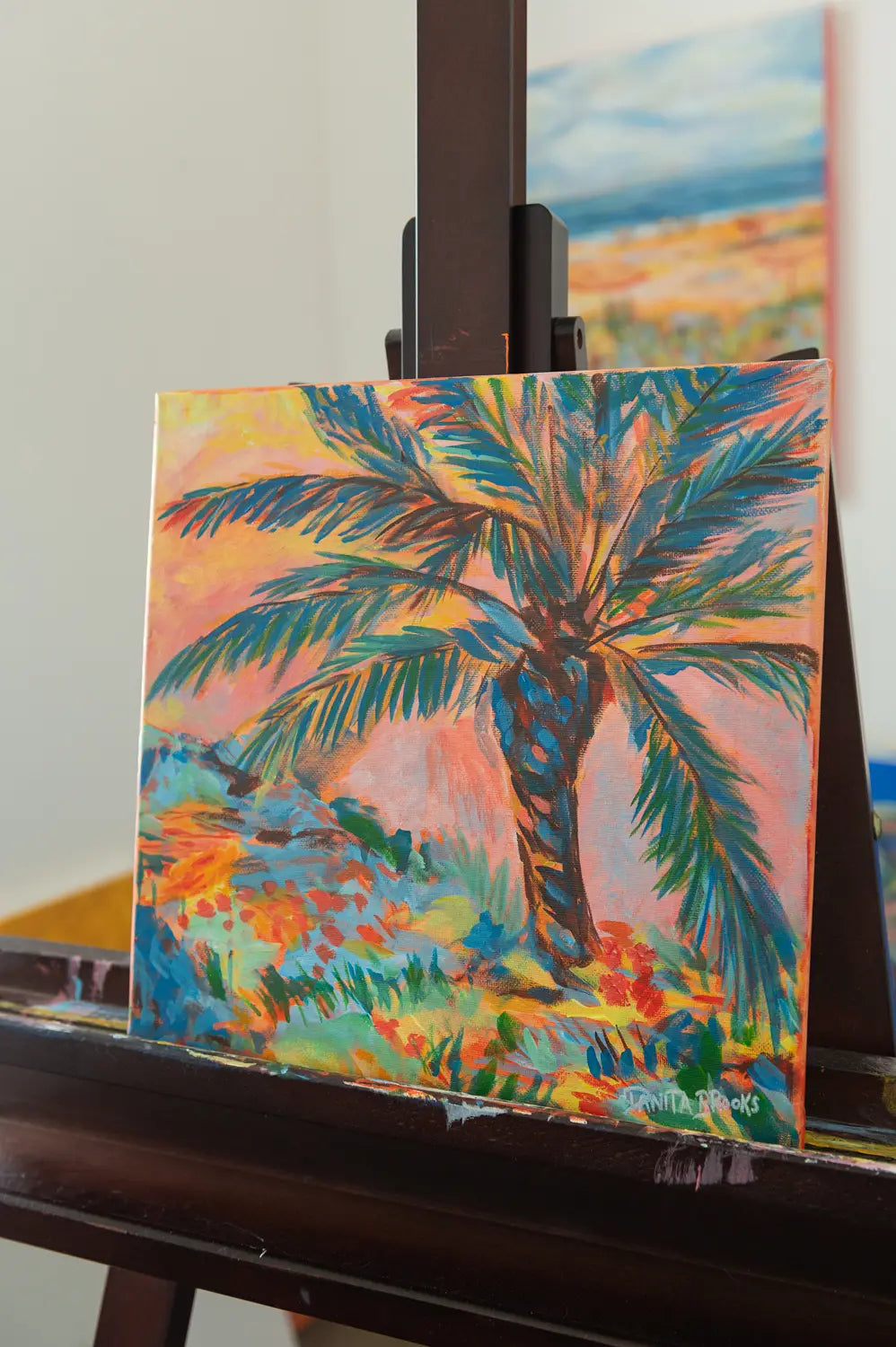 Side view of "Sorbet Skies" acrylic painting showing sunset sky in soft pink, orange, and gold behind a silhouetted palm tree
