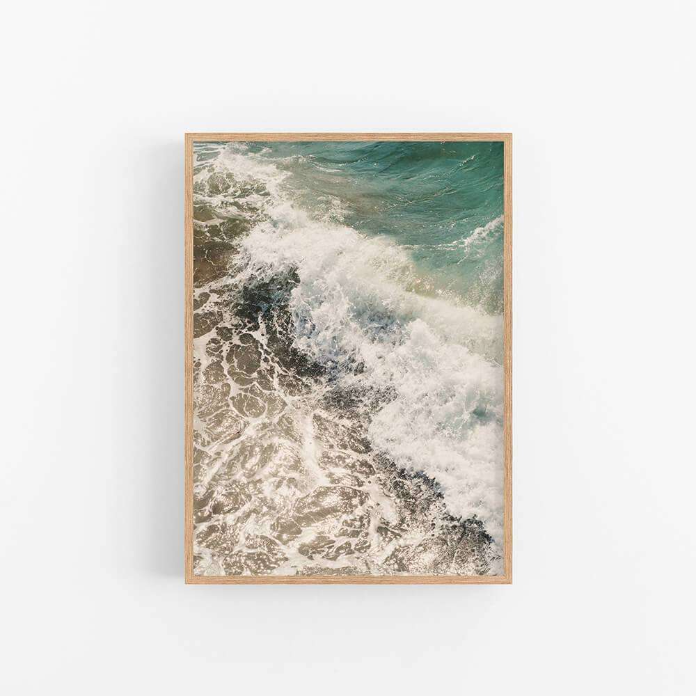 a framed photograph of a wave crashing on the beach